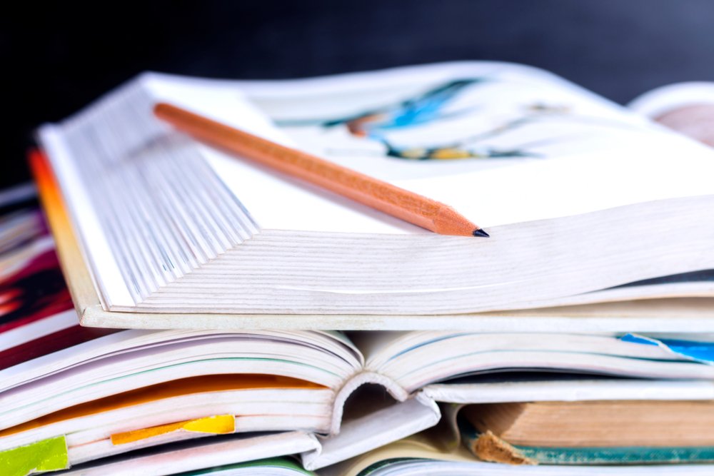 Open hardback and textbook stacked on the table on blackboard background